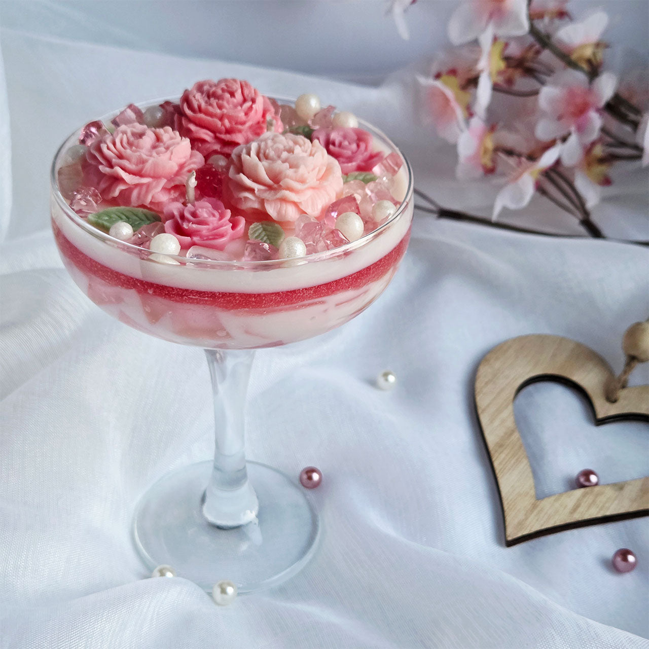 Natürliche Rosenquarz-Steine als dekoratives Element einer floralen Duftkerze