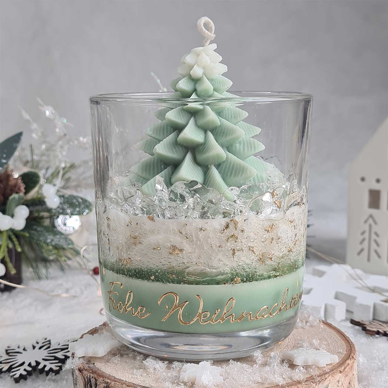 Weihnachtskerze im Glas mit goldenen Details und Winterdeko